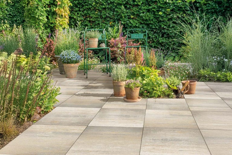 Terras met betonnen platen, planten en tuinstoelen