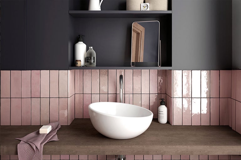 Badkamerweergave met wastafel, kraan, roze wandtegels en opbergplank