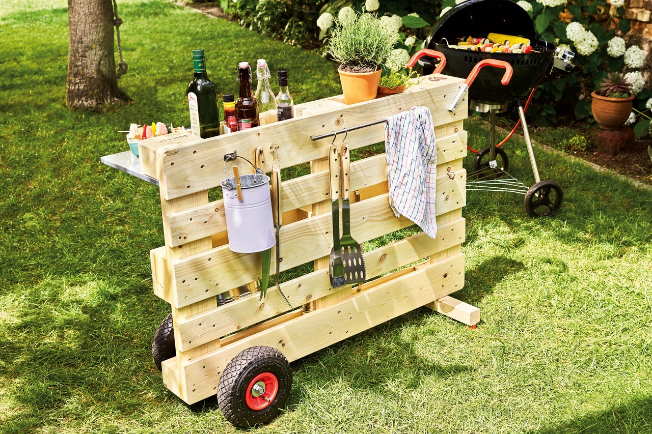 Mobiel barbecue station van houten pallet met barbecue, dranken en accessoires in de tuin