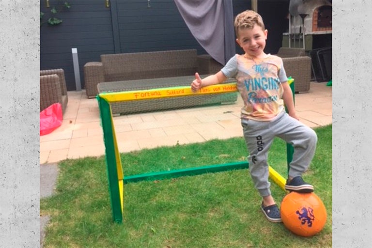 Jongen met voetbal op het gazon voor een voetbaldoel