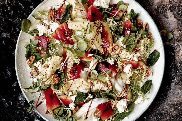 Saladebord met watermeloen, kaas, slabladeren, munt en walnoten