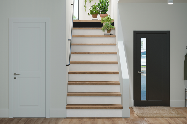 Moderne entree met een witte binnendeur, een donkergrijze voordeur met glas en een trap met houten treden en witte stootborden.