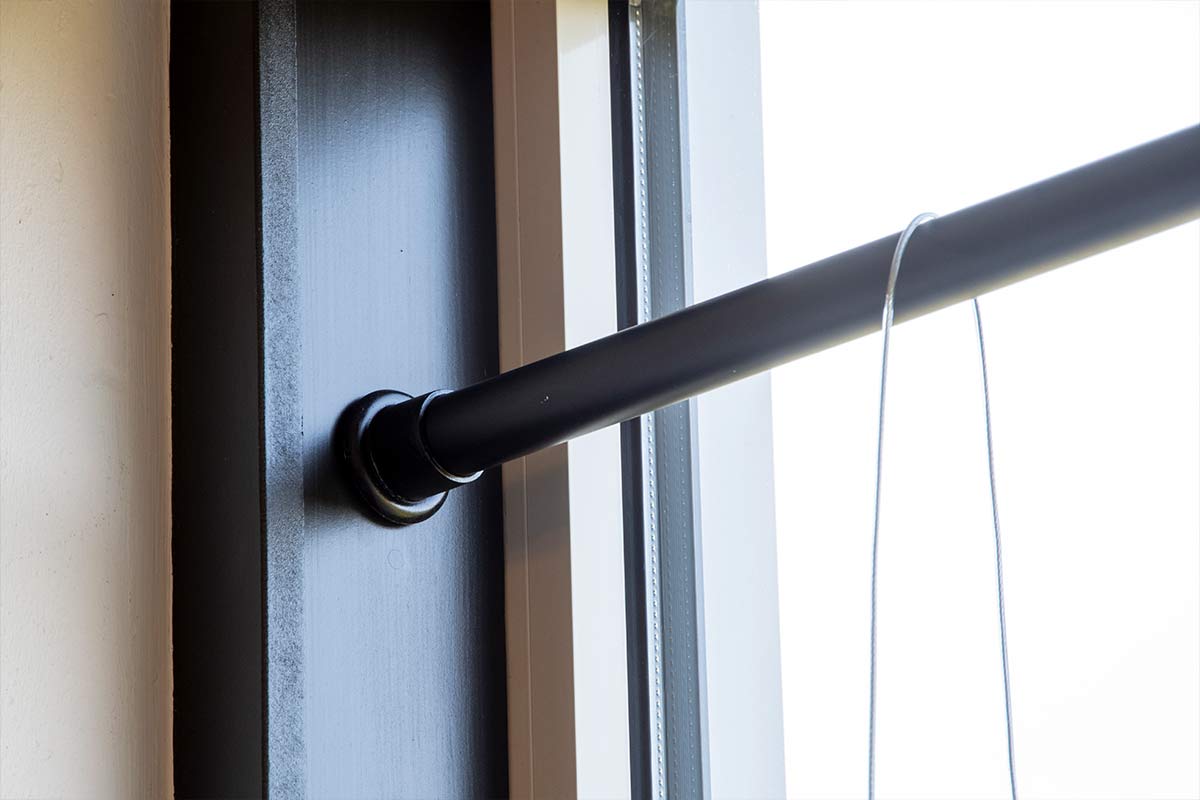 Detailopname van een zwarte kledingroede met wandhouder