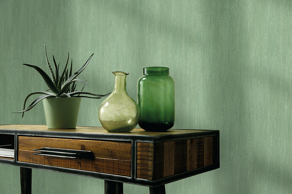Modern interieur met groen structuurbehang, een houten sidetable, een aloë vera plant en glazen vazen.