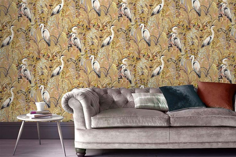 Decoratief behang met reiger- en plantmotieven in een woonkamer met bank en bijzettafel.