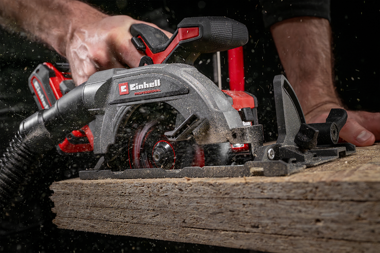 Einhell accu-cirkelzaag snijdt door een houten plaat met aangesloten stofafzuiging.