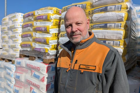 Een man staat voor pallets met zakken verschillende soorten mortel.