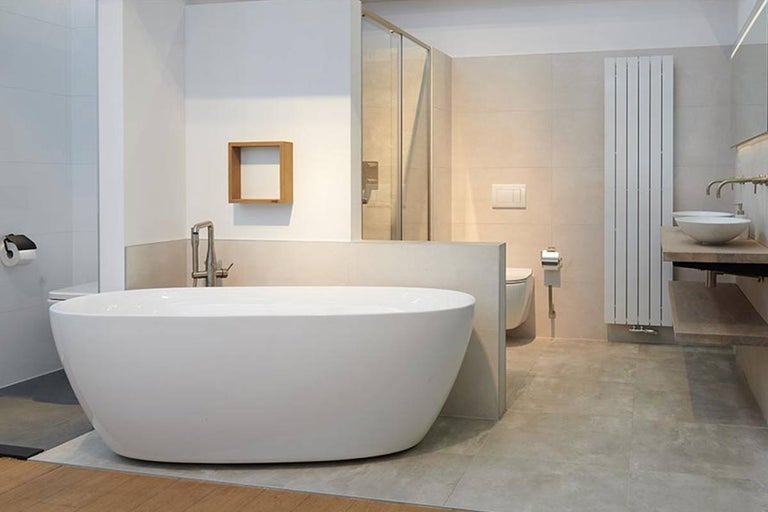 Lichte badkamer met vrijstaand bad, douche, wastafel en radiator