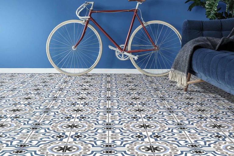 Kameroverzicht met decoratieve vloertegels, rode fiets en blauwe bank.