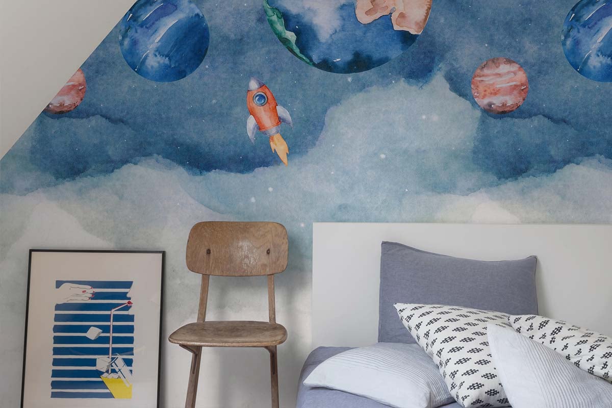 Vliesbehang met ruimtemotief en planeten voor een kinderkamer, aquarelachtige print op een muuroppervlak.