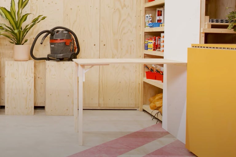 Werkruimte met opklapbare houten tafel, planken en stofzuiger