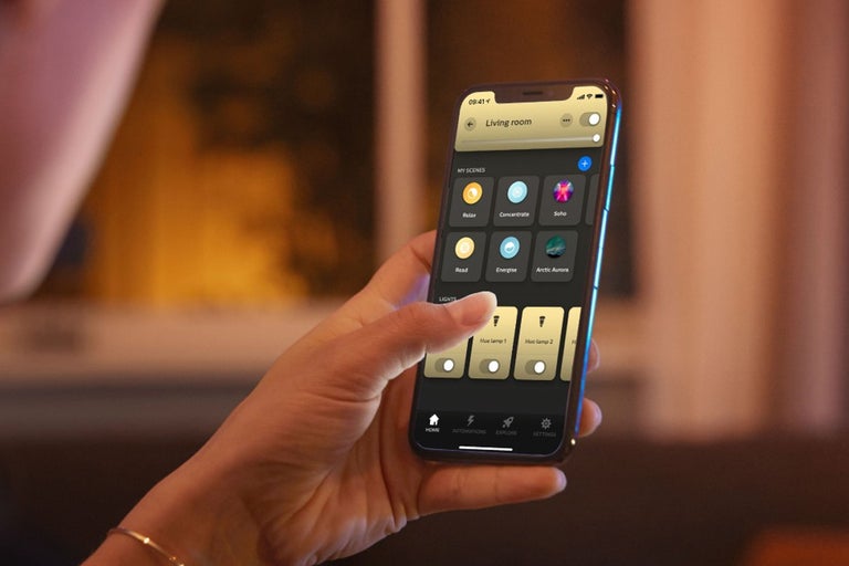 Een persoon houdt een smartphone vast met een app om lampen te bedienen.