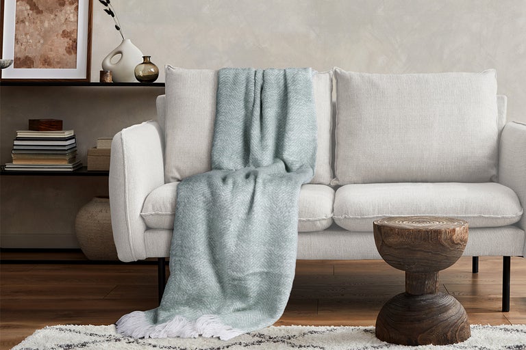 Woonkamer met bank, houten kruk en deken