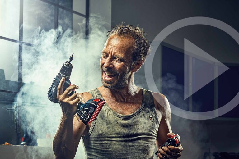 Ambachtsman houdt accuschroefboormachine en accu in zijn handen