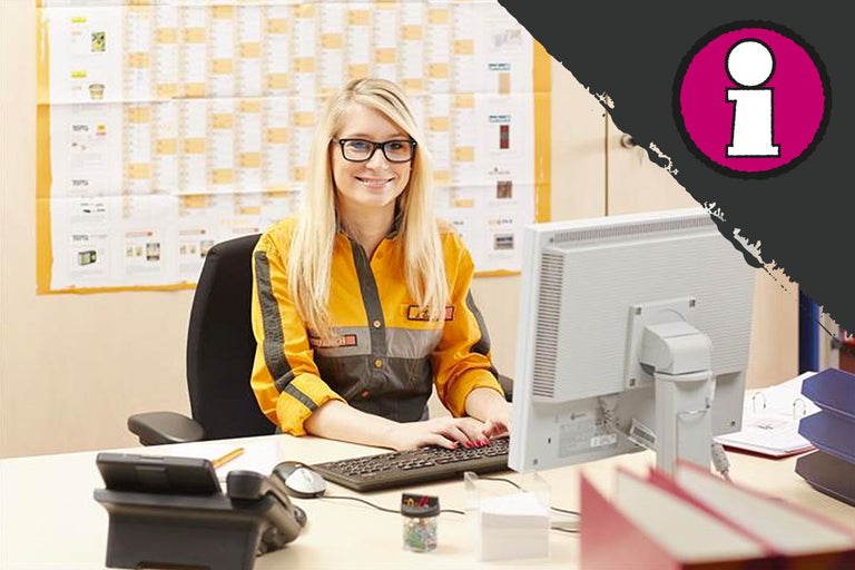 Een vrouw zit aan een bureau met een computer en kantoorbenodigdheden.