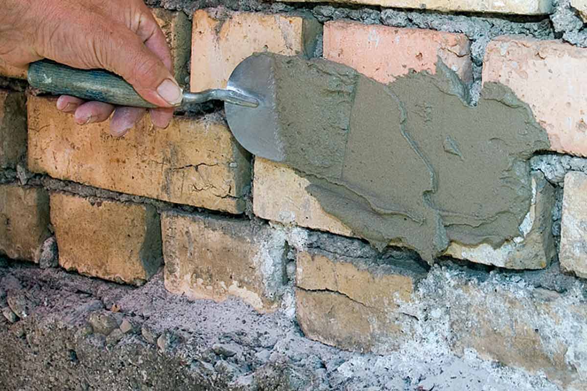 Metselaar repareert bakstenen muur met troffel en mortel