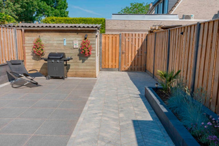 Tuin met terras, barbecue en houten schutting
