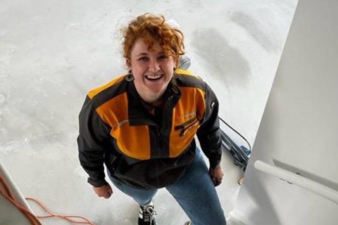 Een vrouw draagt een werkjas en staat op een verzegelde vloer.