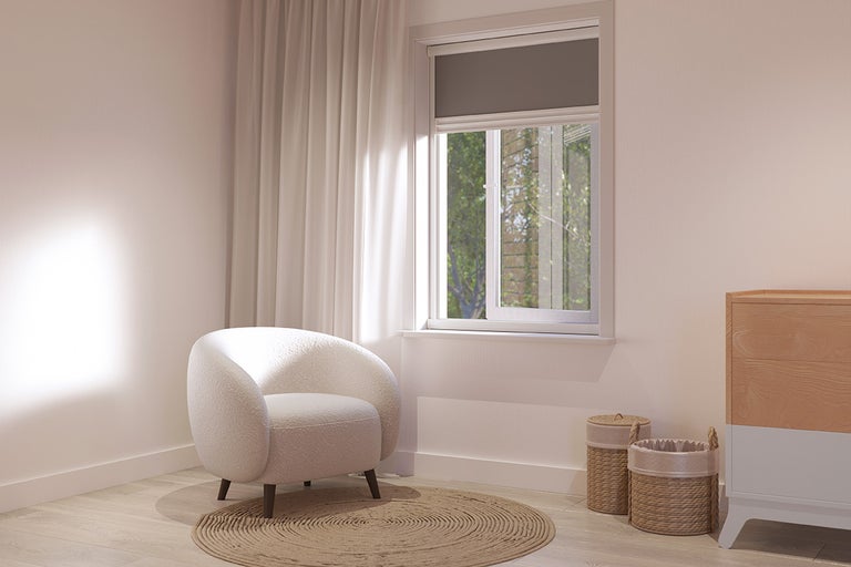 Lichte kamer met fauteuil, rond vloerkleed, rolgordijn voor het raam en commode