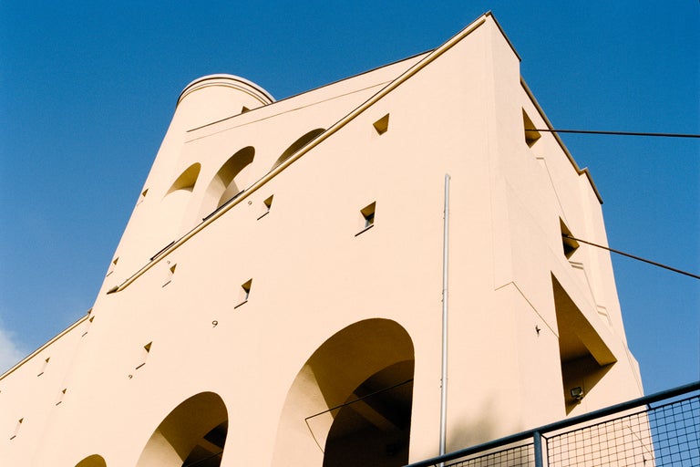 Buitenkant van een gebouw met bogen en een toren onder een blauwe hemel