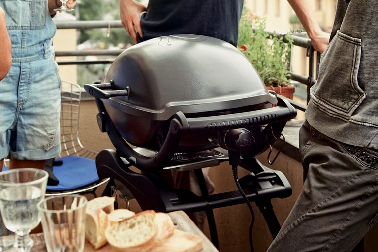 Elektrische barbecue op een balkon met brood en drankjes op tafel