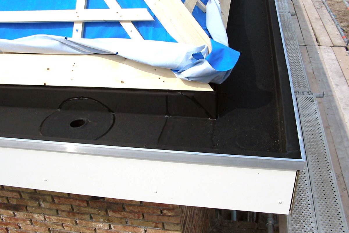 Detailopname van een plat dak met afdichting, dakrand en dakgoot.