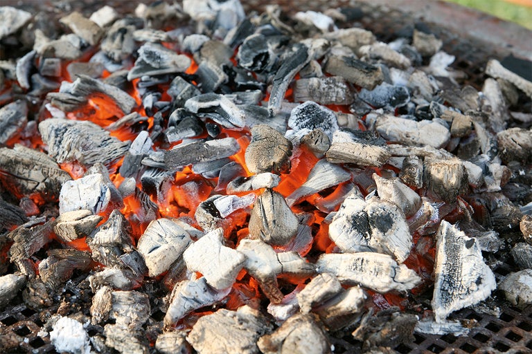 Gloeiende houtskool op een grillrooster