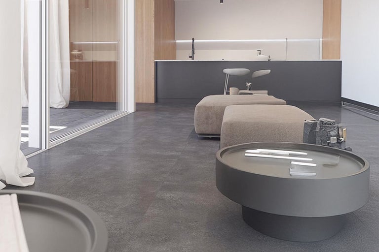 Woonkamer met grijze vloertegels, poefs en salontafel