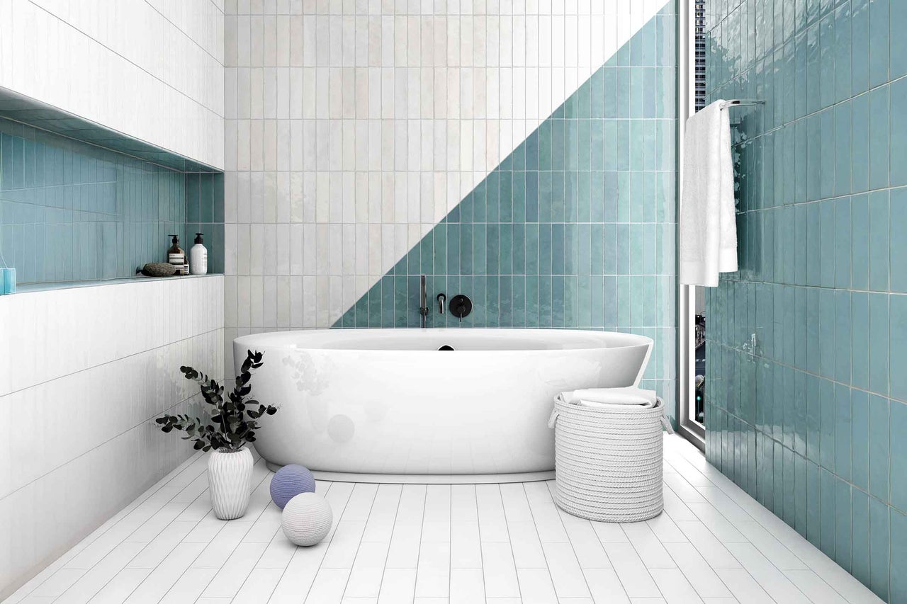 Moderne badkamer met witte en groene tegels, vrijstaand bad en decoratieve elementen.