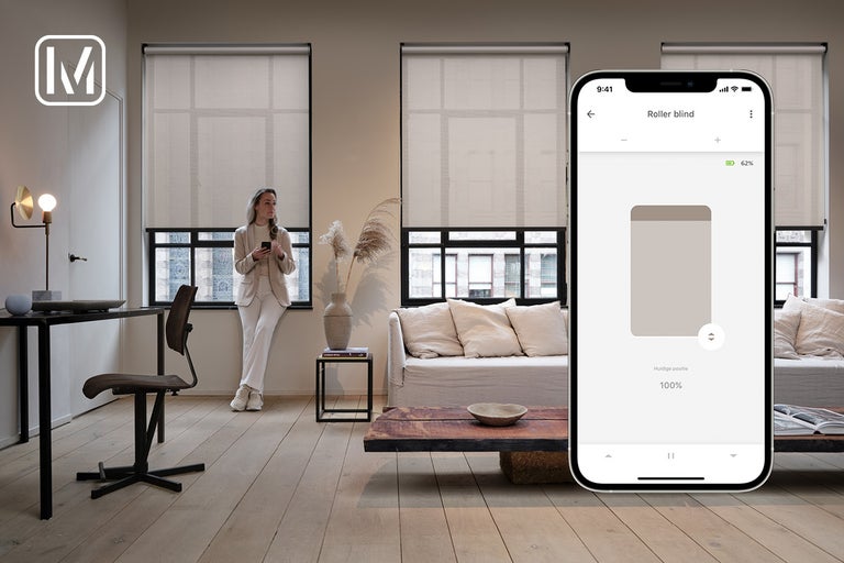 Woonkamer met raamrolgordijnen en smartphone met app om de rolgordijnen te bedienen