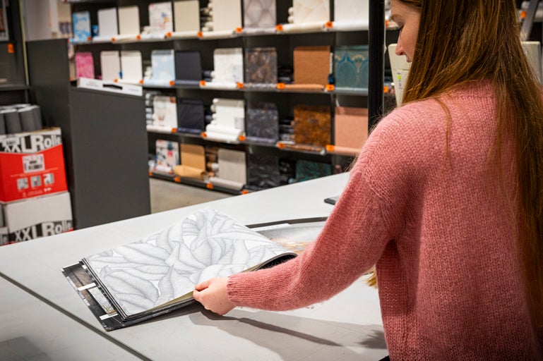 Klant bladert door een behangstalenboek in de Hornbach vestiging.