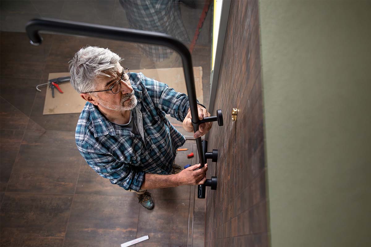 Vakman monteert een zwarte douchekraan op een betegelde wand in een badkamer.