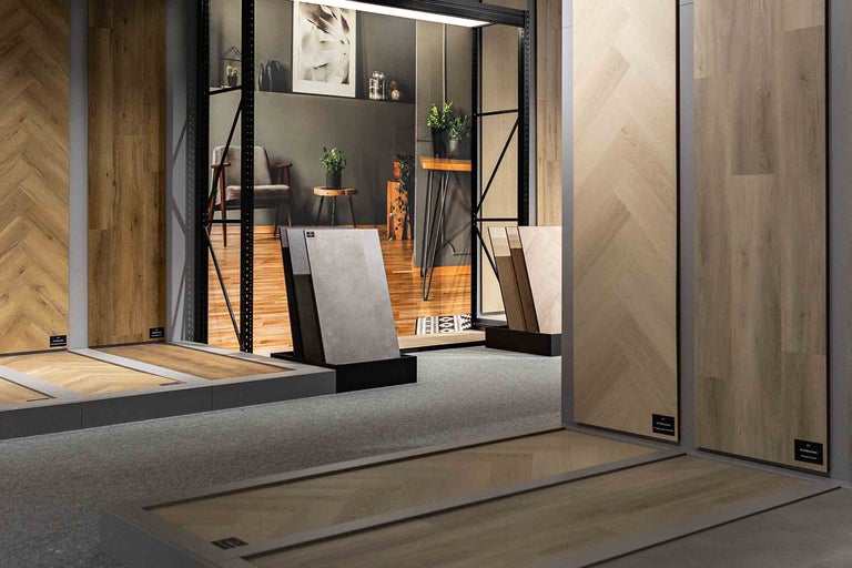 Tentoonstelling van vloerbedekkingen met verschillende houtmotieven en texturen in een lichte, ruime kamer