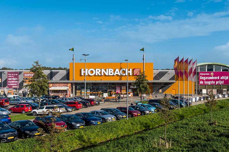 Hornbach bouwmarkt met parkeerplaats en reclame voor laagste prijzen.