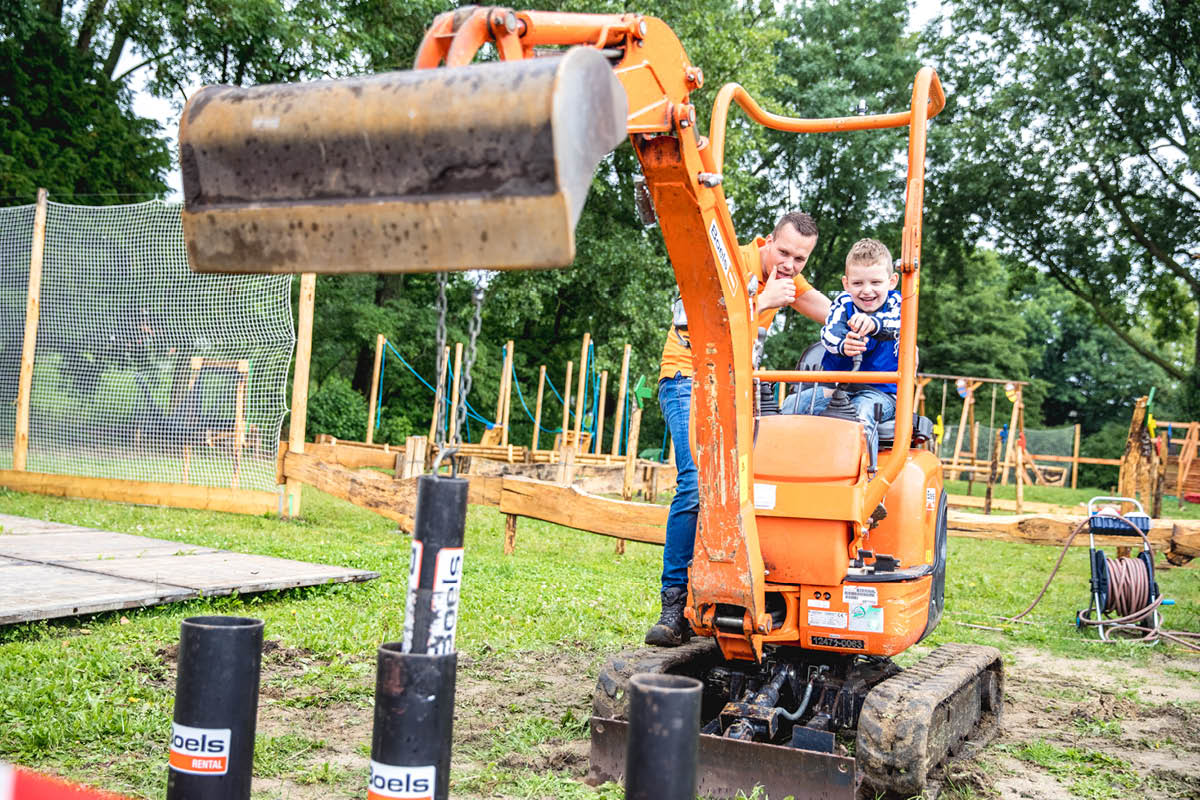 Vader en zoon bedienen een minigraver op een bouwplaats in de open lucht