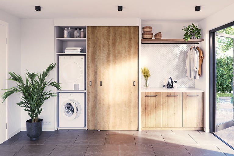 Lichte wasruimte met wasmachine, droger, inbouwkasten en kamerplant