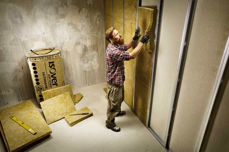 Man installeert Isover isolatiewol in een kamer.