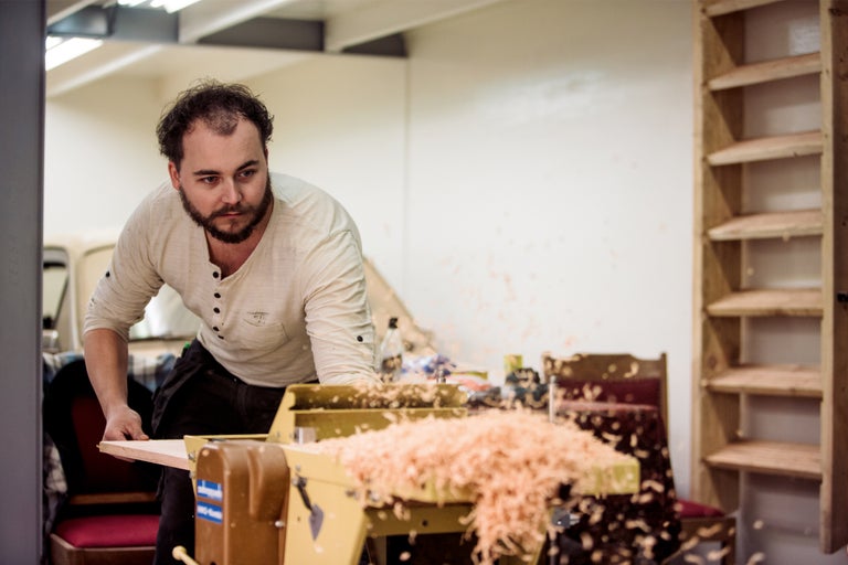 Man werkt met een houtdraaibank in een werkplaats en er ontstaan houtsnippers.