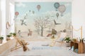 Behang in kinderkamer met illustraties van bosdieren en heteluchtballonnen in een lichte, vriendelijke sfeer.