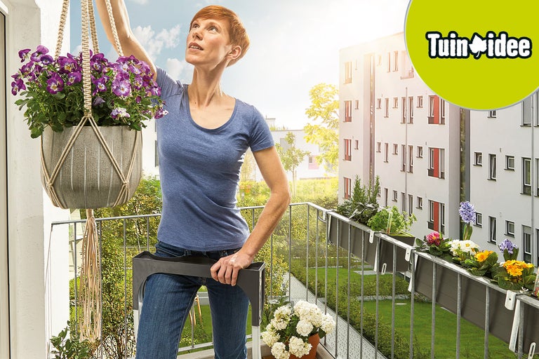 Vrouw richt balkon in met hangpot en bloembakken