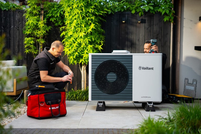 Installatie van een Vaillant warmtepomp in de tuin door twee vakmensen.
