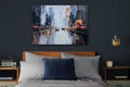 Slaapkamer met bed, nachtkastjes, lamp en een schilderij van een stadsgezicht.