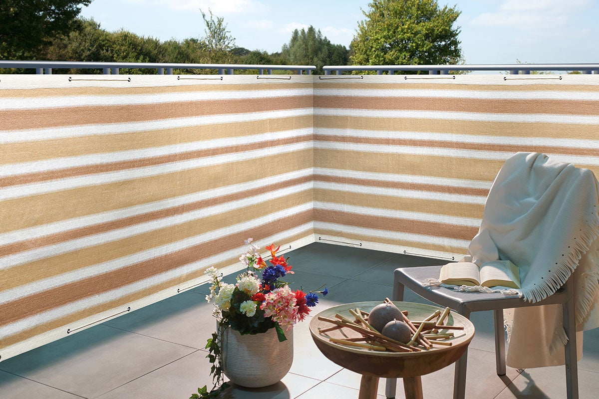 Terras met gestreepte privacy scherm, stoel, deken en decoratie