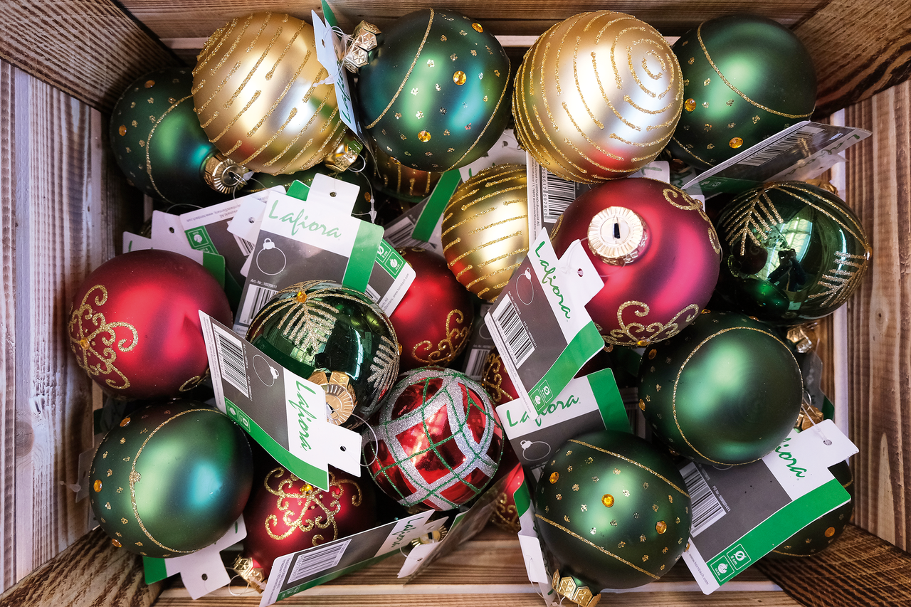 Houten kist gevuld met rode, groene en gouden kerstballen met decoratie