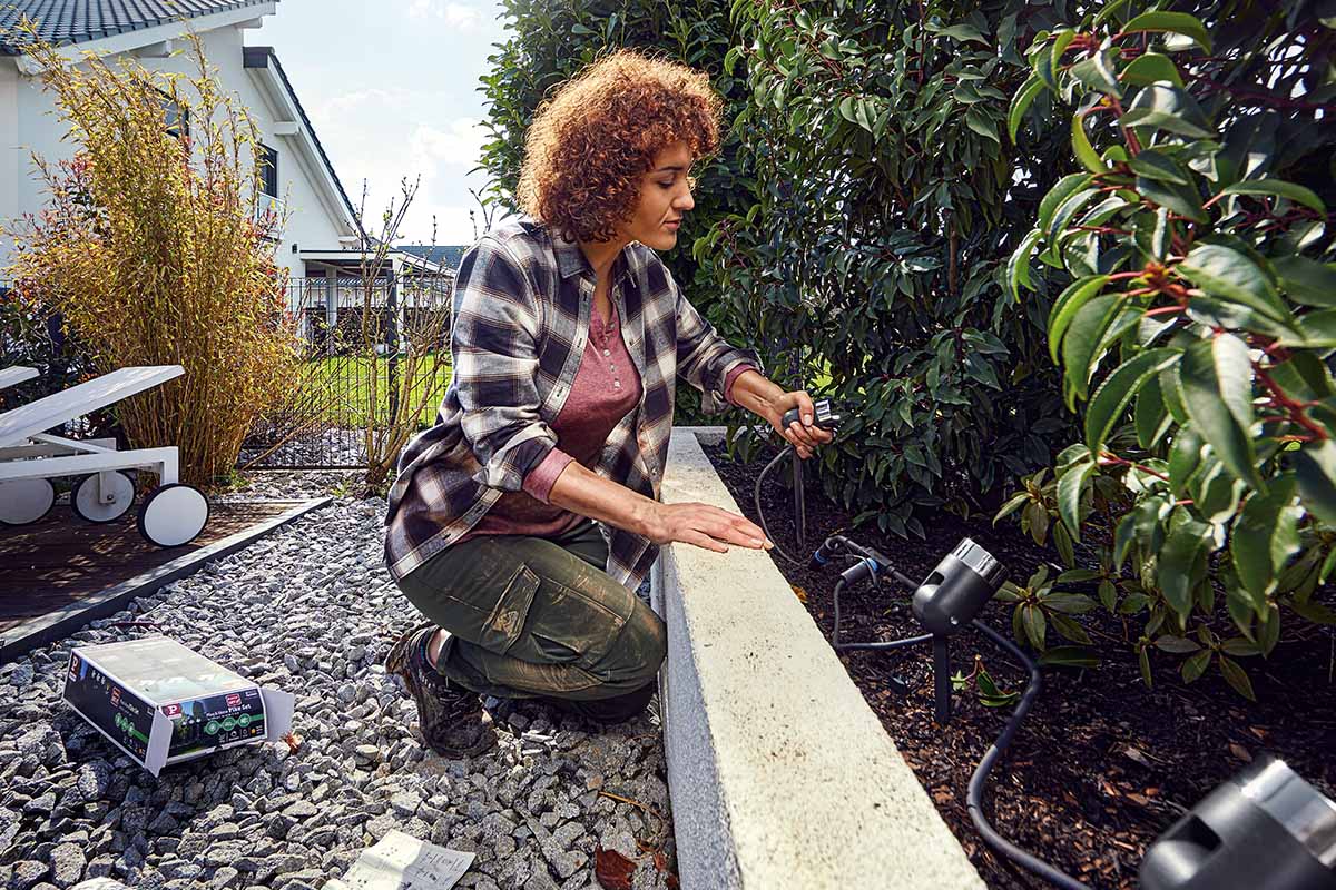 Vrouw installeert tuinverlichting in de tuin