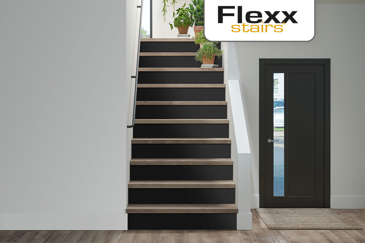 Moderne trap met donkere stootborden, lichte houtlook treden en een donkere binnendeur met glas. Flexx stairs Logo.