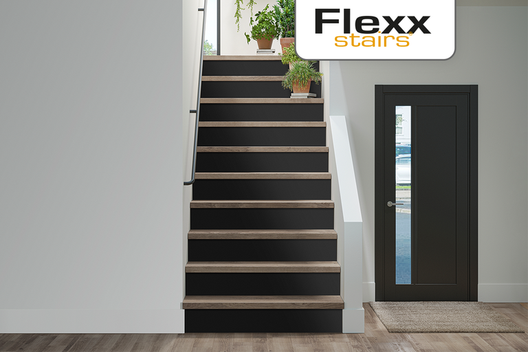 Moderne trap met donkere stootborden, lichte houtlook treden en een donkere binnendeur met glas. Flexx stairs Logo.