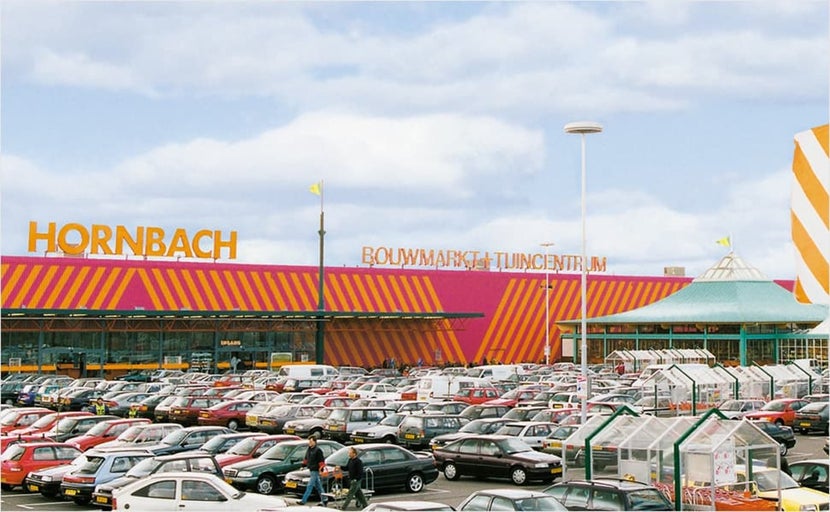 Buitenaanzicht van een Hornbach bouw- en tuinmarkt met een volle parkeerplaats.