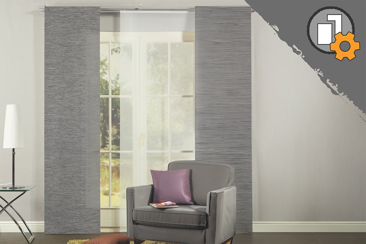 Grijze paneelgordijnen met structuur en wit transparant paneel voor een raam in een moderne kamer met fauteuil. Product individueel configureerbaar.