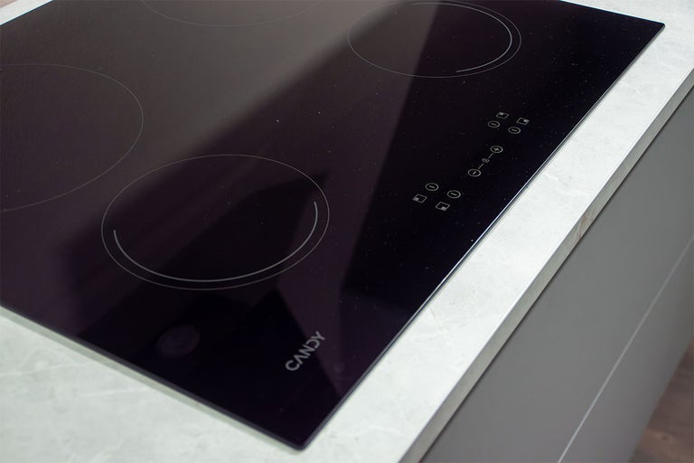 Glaskeramische kookplaat van Candy met vier kookzones en tiptoetsbediening, ingebouwd in een werkblad. Candy Logo.